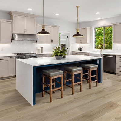 light hardwood flooring in kitchen with cream cabinets and white stone island with wood stools.