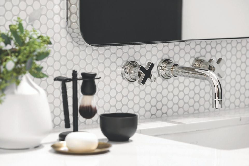 Close up of chrome sink with white round white tile in modern black and white bathroom 